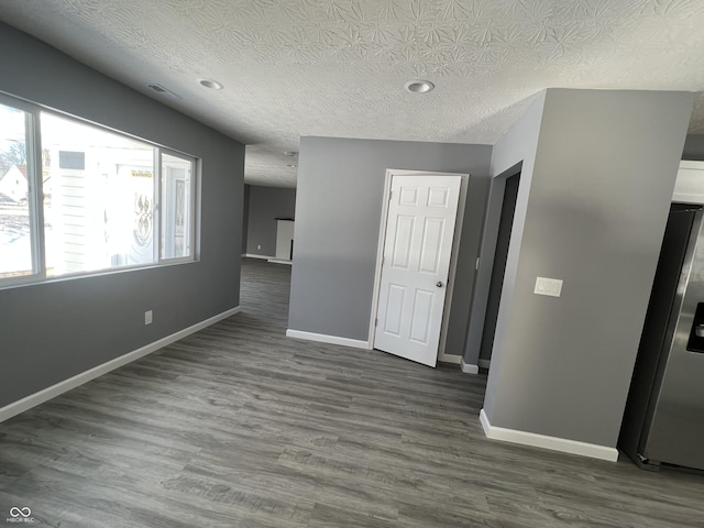 unfurnished room with a textured ceiling and dark hardwood / wood-style flooring