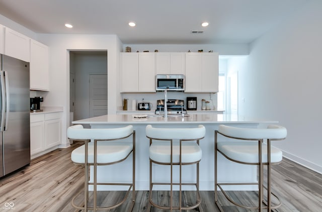 kitchen with an island with sink, appliances with stainless steel finishes, and white cabinets