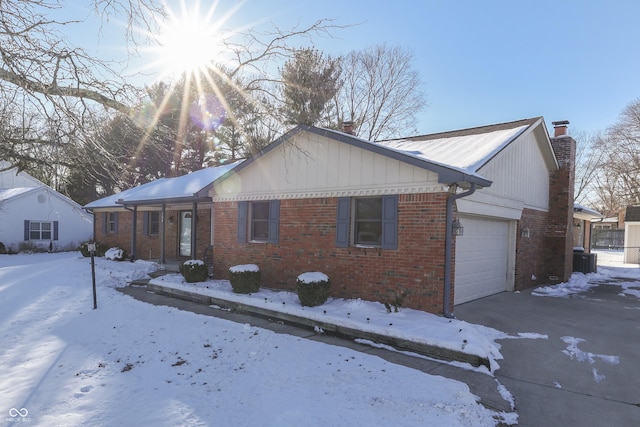 view of snowy exterior featuring a garage and cooling unit