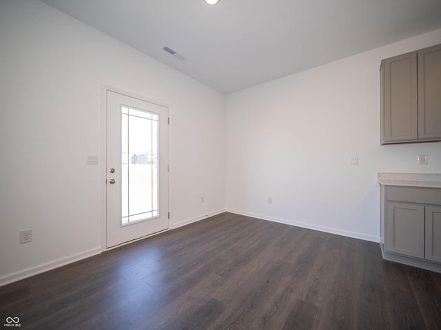 unfurnished living room featuring visible vents, baseboards, and dark wood-style flooring