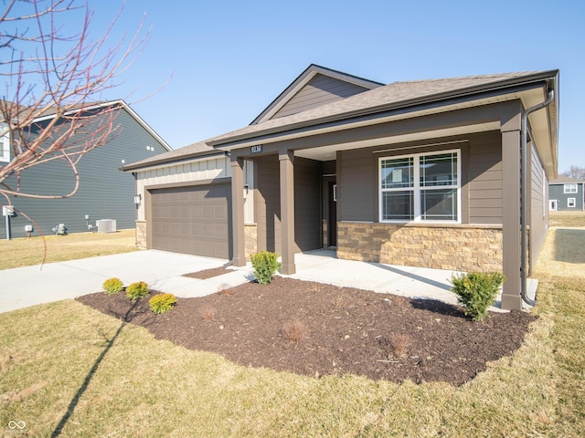 view of front facade with stone siding, an attached garage, driveway, and a front yard