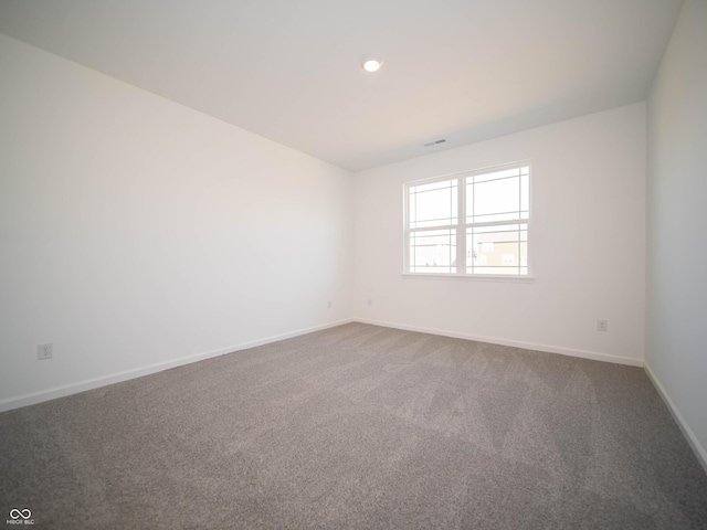 spare room featuring dark colored carpet, visible vents, baseboards, and recessed lighting