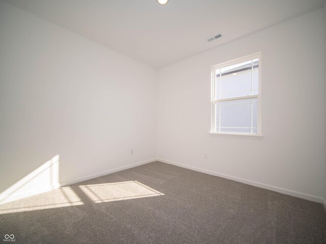 carpeted spare room featuring visible vents and baseboards