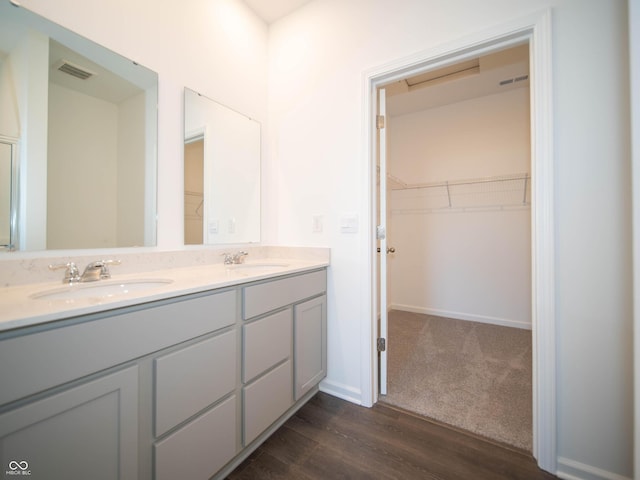 full bath with a walk in closet, double vanity, visible vents, and a sink