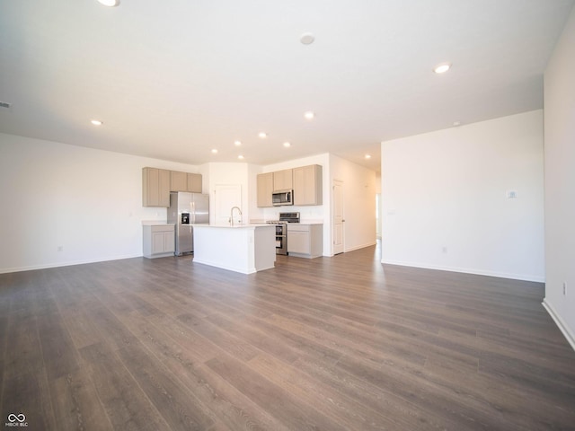 unfurnished living room with dark wood finished floors, recessed lighting, baseboards, and a sink