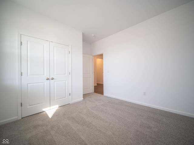 unfurnished bedroom featuring carpet, baseboards, and a closet