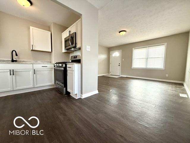 kitchen with stainless steel appliances, sink, white cabinets, and dark hardwood / wood-style flooring