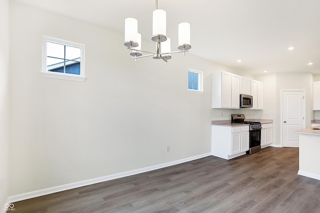 kitchen with pendant lighting, appliances with stainless steel finishes, white cabinetry, dark hardwood / wood-style flooring, and a notable chandelier