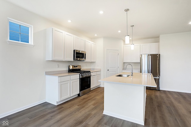 kitchen featuring pendant lighting, appliances with stainless steel finishes, white cabinets, sink, and a kitchen island with sink