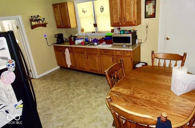 kitchen with black fridge and light colored carpet