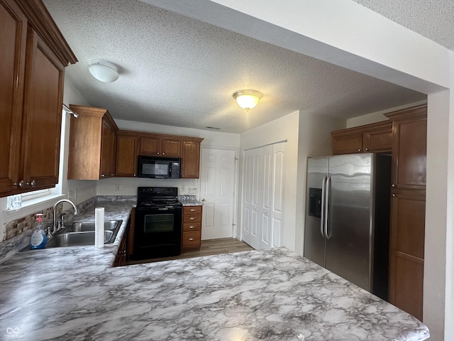 kitchen featuring sink, a textured ceiling, black appliances, and kitchen peninsula