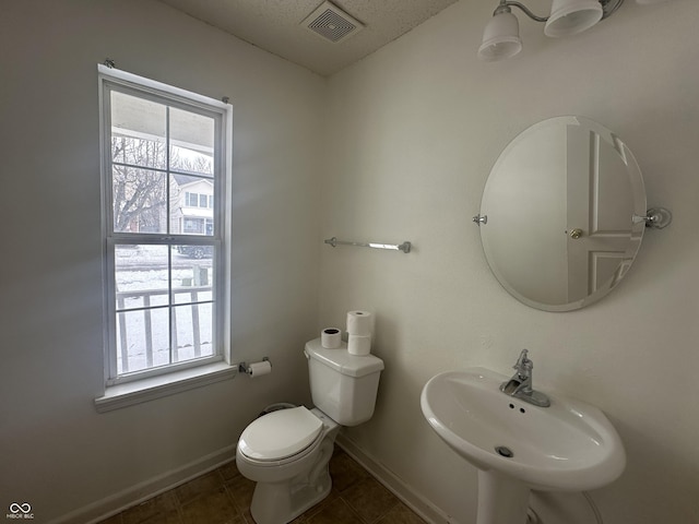 bathroom with sink, a healthy amount of sunlight, tile patterned flooring, and toilet