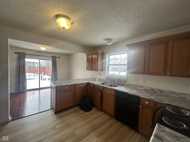 kitchen featuring kitchen peninsula, a textured ceiling, black appliances, light wood-type flooring, and sink