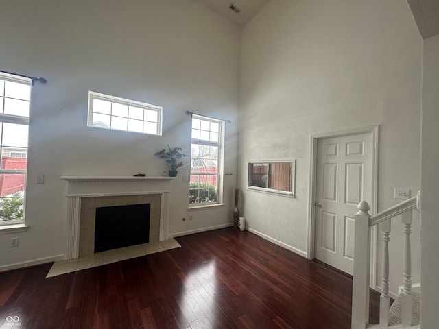 unfurnished living room featuring dark hardwood / wood-style flooring, high vaulted ceiling, and a fireplace