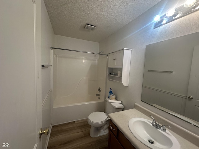 full bathroom featuring toilet, hardwood / wood-style flooring, a textured ceiling,  shower combination, and vanity