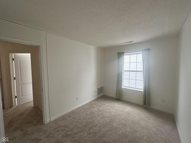 spare room with a textured ceiling and carpet flooring