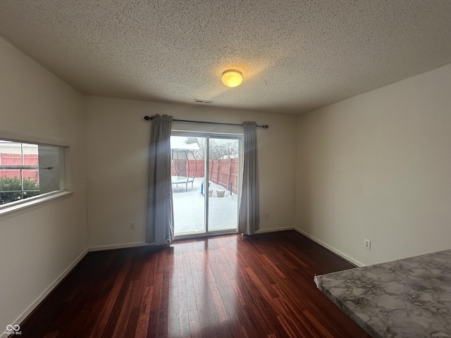 empty room featuring a textured ceiling and dark wood-type flooring