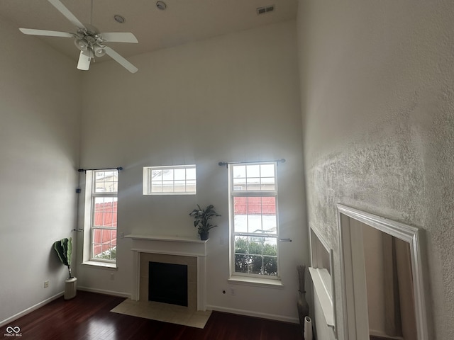 unfurnished living room with a high ceiling, ceiling fan, and dark hardwood / wood-style flooring