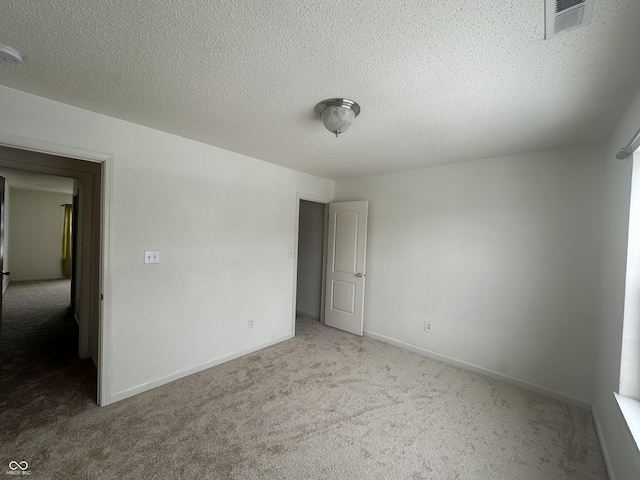 unfurnished room featuring a textured ceiling and carpet