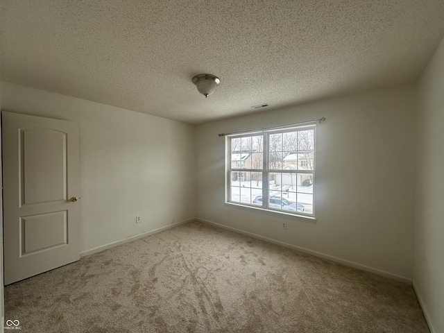 spare room with a textured ceiling and light carpet