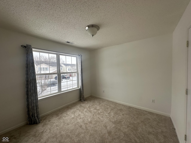 unfurnished room featuring light colored carpet and a textured ceiling