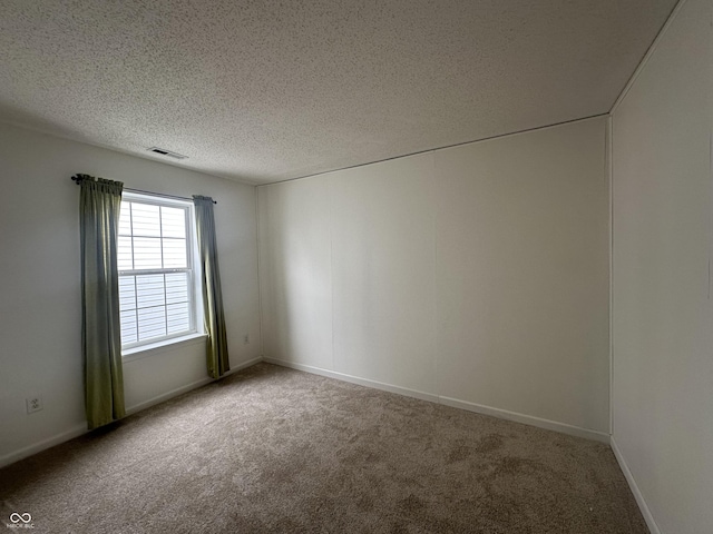 carpeted empty room featuring a textured ceiling