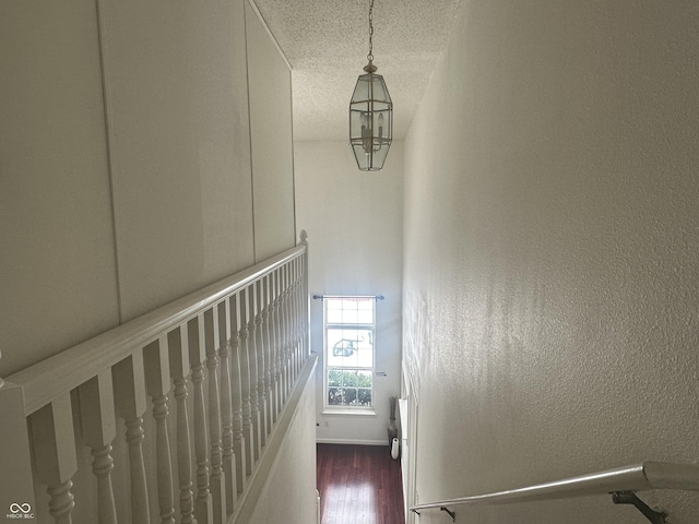 stairway with wood-type flooring and a textured ceiling