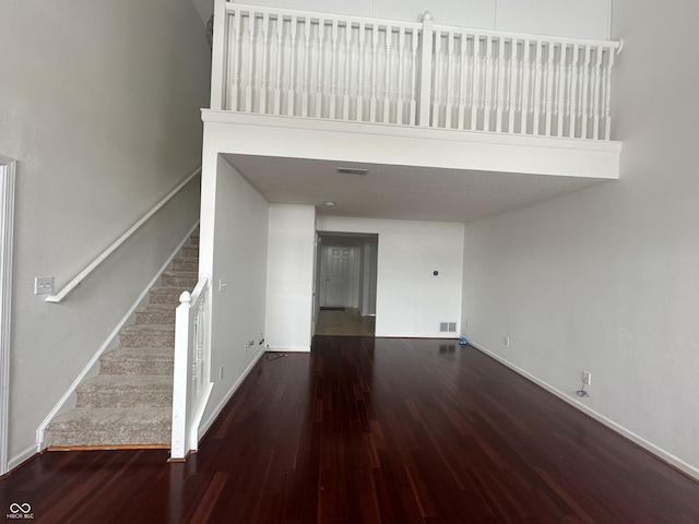 unfurnished living room with a towering ceiling and dark hardwood / wood-style floors