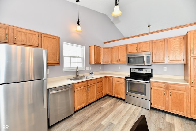 kitchen with decorative light fixtures, high vaulted ceiling, light wood-type flooring, appliances with stainless steel finishes, and sink