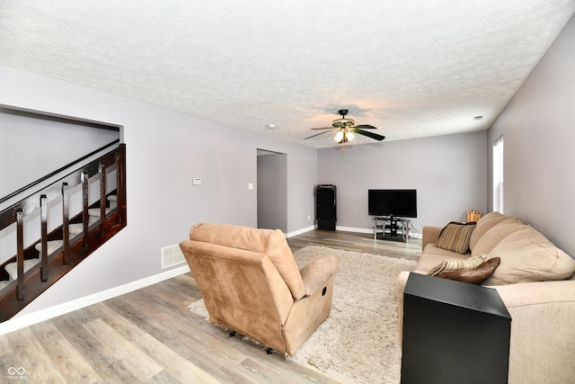 living room with a textured ceiling, ceiling fan, and hardwood / wood-style flooring