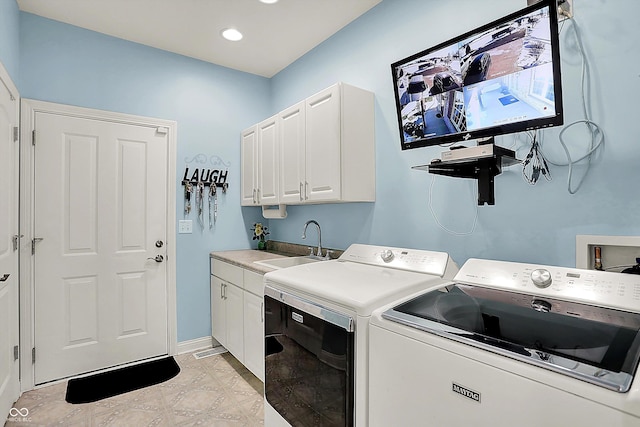 clothes washing area featuring sink, washer and clothes dryer, and cabinets