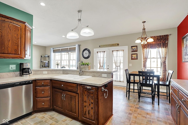 kitchen featuring sink, decorative light fixtures, stainless steel dishwasher, a chandelier, and plenty of natural light