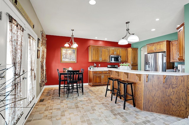 kitchen with stainless steel appliances, a kitchen bar, and pendant lighting