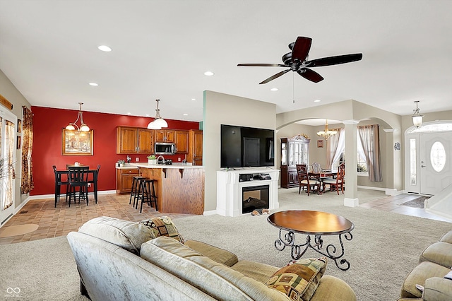 living room with light colored carpet and ceiling fan with notable chandelier