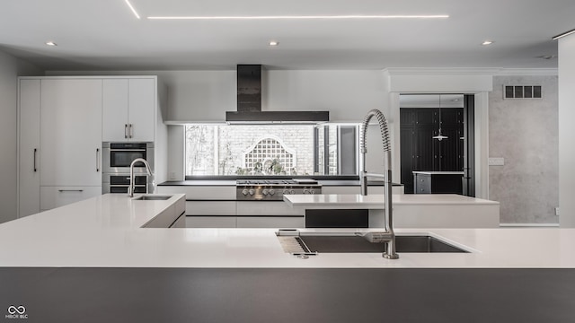 kitchen with white cabinets, wall chimney exhaust hood, sink, and stainless steel double oven