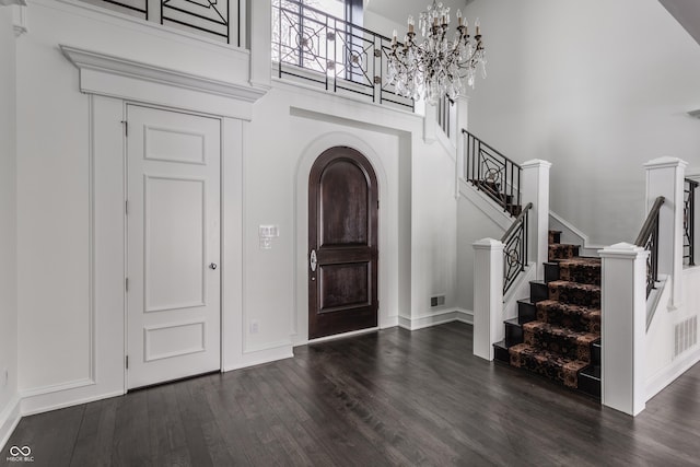 foyer entrance with a towering ceiling and dark hardwood / wood-style floors