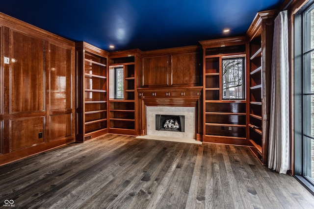 unfurnished living room featuring dark hardwood / wood-style flooring, a fireplace, and wood walls