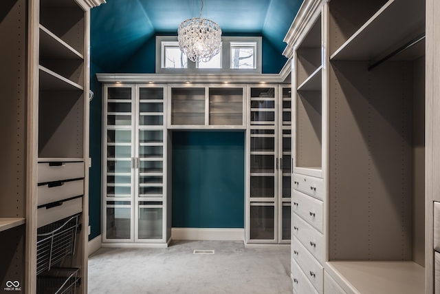 spacious closet featuring a notable chandelier and vaulted ceiling