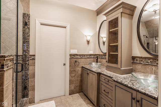 bathroom with tile walls, an enclosed shower, vanity, and tile patterned flooring