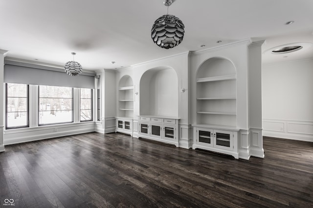 unfurnished living room featuring built in shelves, dark hardwood / wood-style floors, crown molding, and a notable chandelier