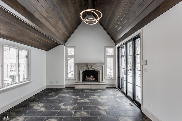 unfurnished living room with lofted ceiling, a healthy amount of sunlight, a chandelier, and wooden ceiling