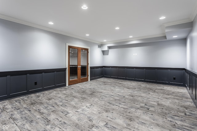 empty room featuring light wood-type flooring, ornamental molding, and french doors