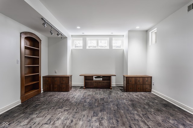 unfurnished room with a healthy amount of sunlight, dark hardwood / wood-style floors, and rail lighting