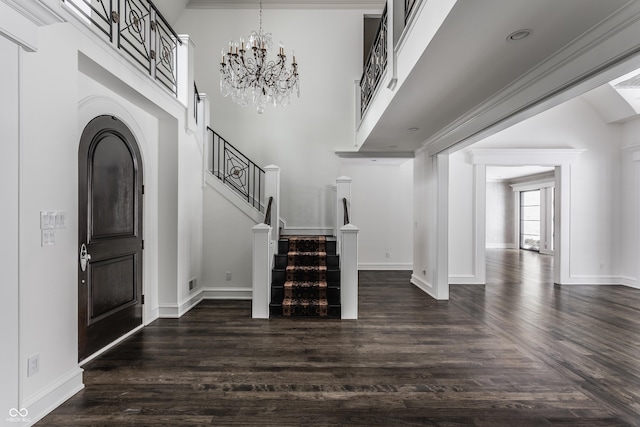 entrance foyer featuring dark hardwood / wood-style floors, ornamental molding, and an inviting chandelier