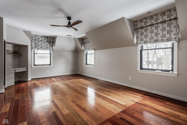 additional living space featuring vaulted ceiling, a healthy amount of sunlight, and hardwood / wood-style floors