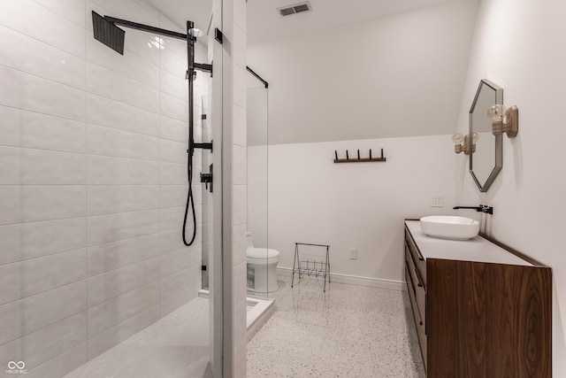 bathroom with toilet, vanity, and tiled shower