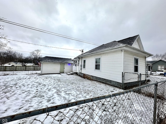 snow covered back of property featuring an outdoor structure