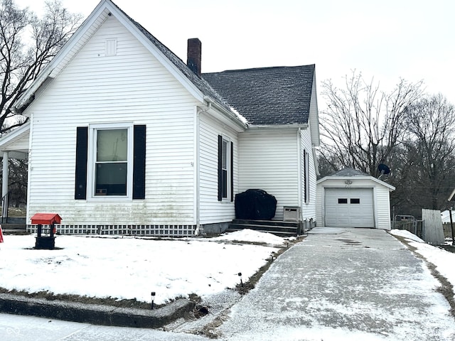 snow covered property featuring an outbuilding and a garage