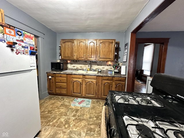 kitchen featuring tasteful backsplash, sink, black appliances, and dark stone counters