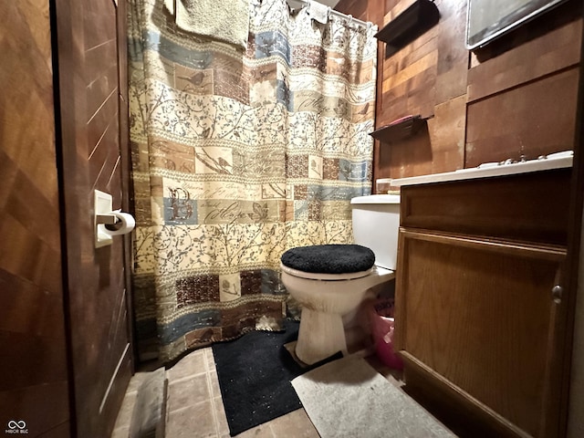 bathroom with vanity, tile patterned floors, wooden walls, and toilet